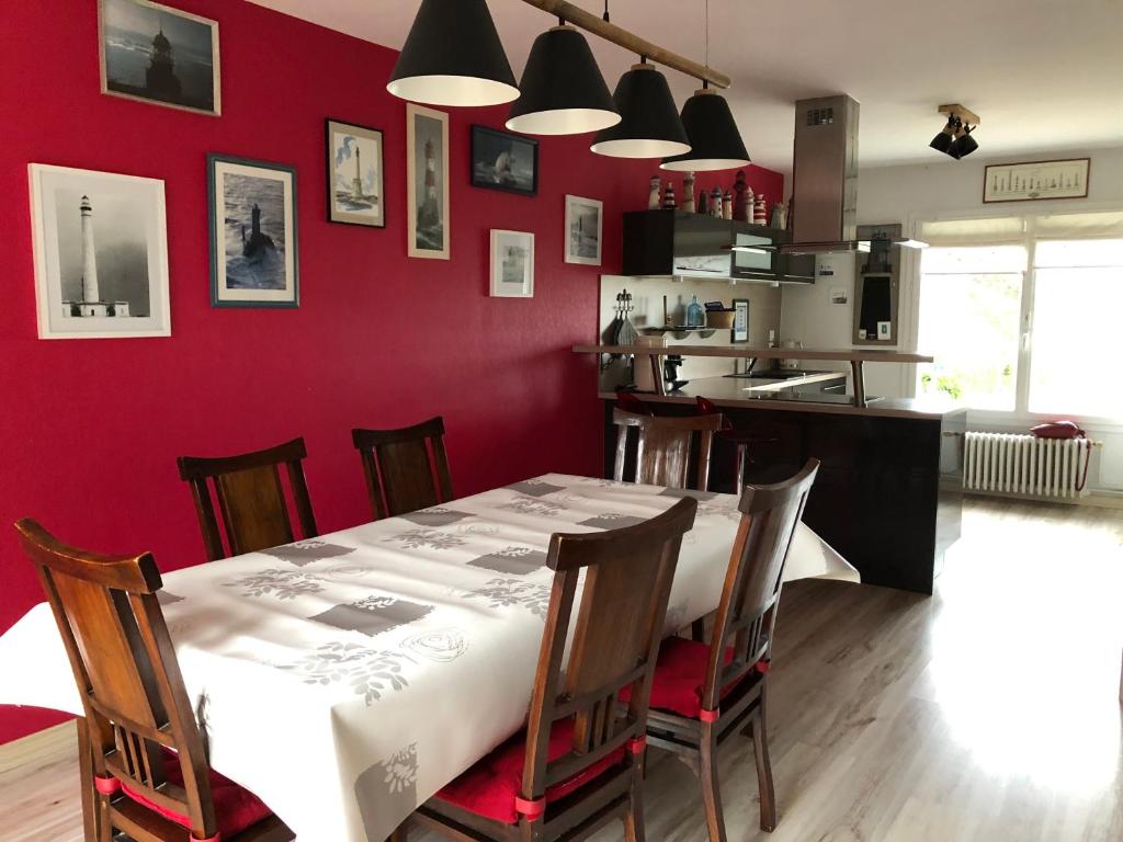 a dining room with a table and a red wall at La Maison des phares in Lion-sur-Mer