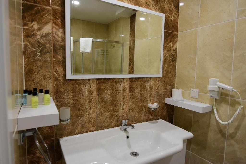 een badkamer met een wastafel en een spiegel bij KALİYE ASPENDOS HOTEL in Antalya