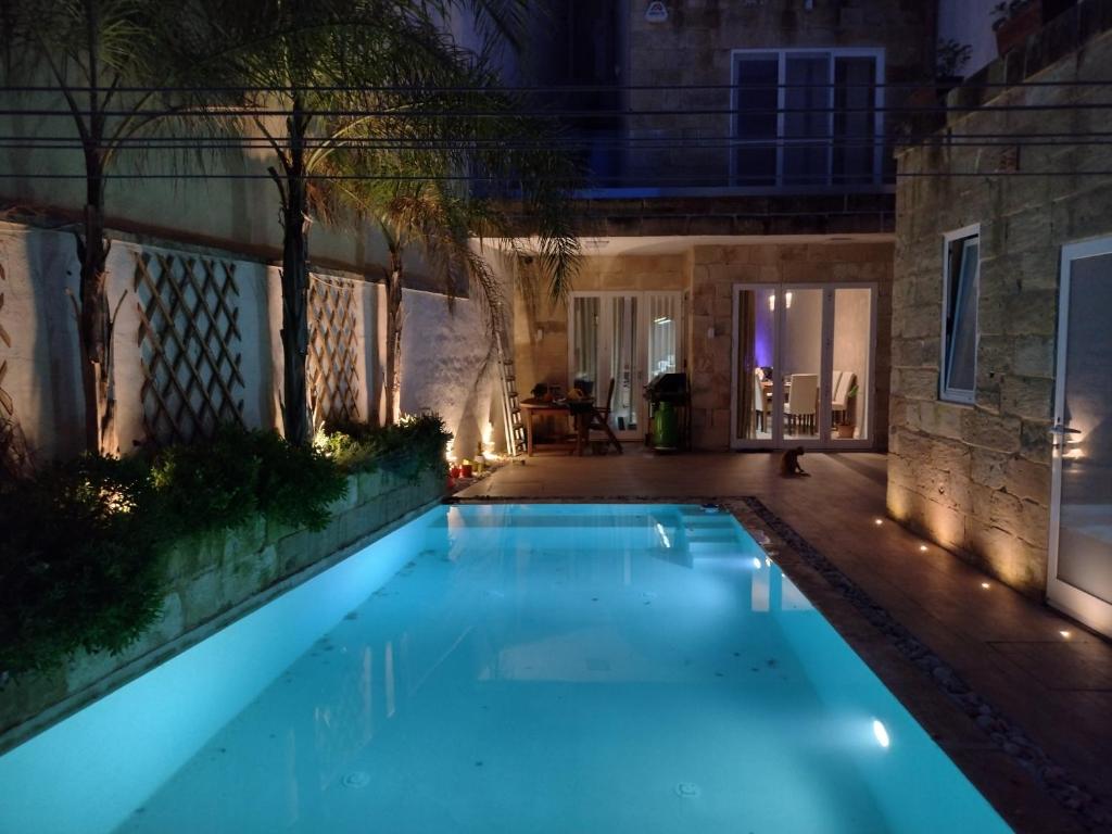 a swimming pool in a backyard at night at The Luxury Home - Next to airport! in Kirkop