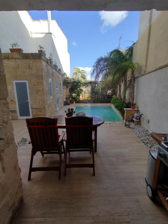 a patio with a table and chairs and a swimming pool at The Luxury Home - Next to airport! in Kirkop