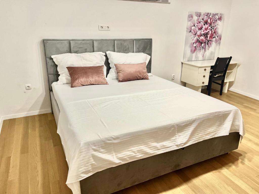 een slaapkamer met een groot bed met witte lakens en roze kussens bij Viktor apartment in Split