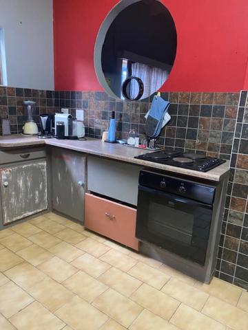 - une cuisine avec une cuisinière et un mur rouge dans l'établissement KleinHenties, à Henties Bay