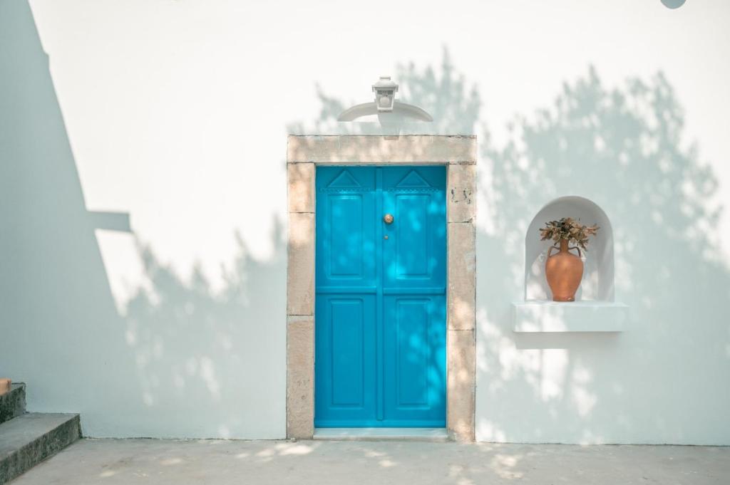 una puerta azul en una pared blanca con un jarrón en Villa Historica en Asfendioú