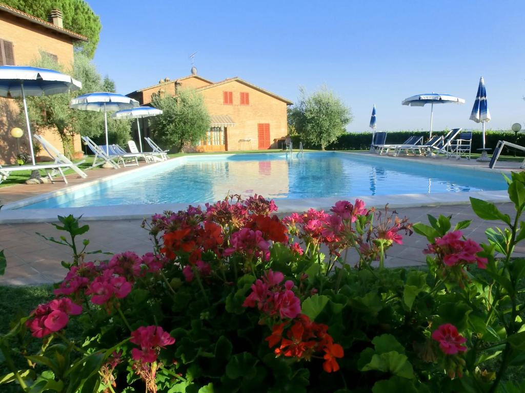 einen Pool mit Blumen und Sonnenschirmen in der Unterkunft Agriturismo Azienda Agricola La Roccaia in San Gimignano