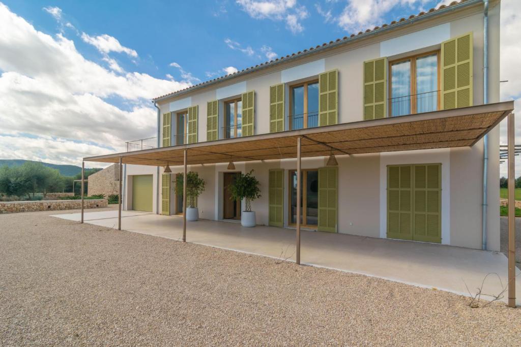 una casa con ventanas verdes y blancas en Can Mosca, en Cala Mendia