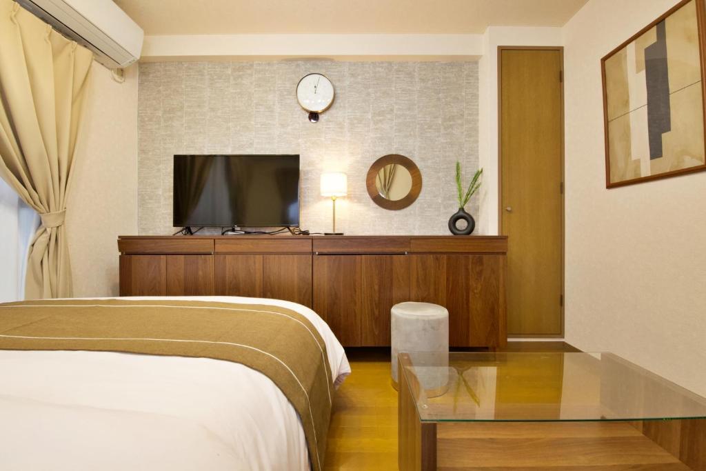 1 dormitorio con 1 cama y TV en la pared en 大井町アパートメントホテル豊強ビル301 en Tokio