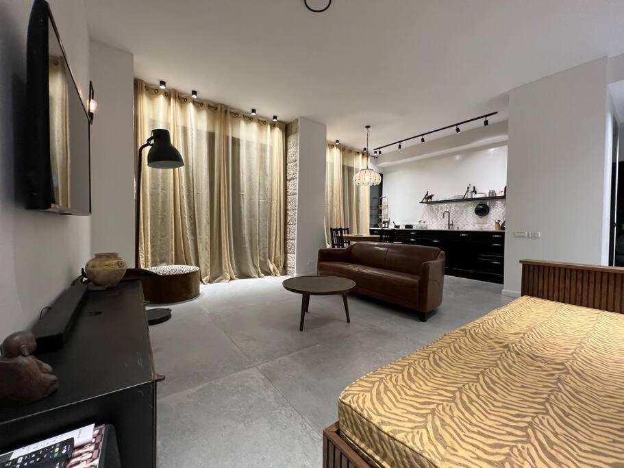 a bedroom with a bed and a living room with a couch at Rosa’s place in Jerusalem