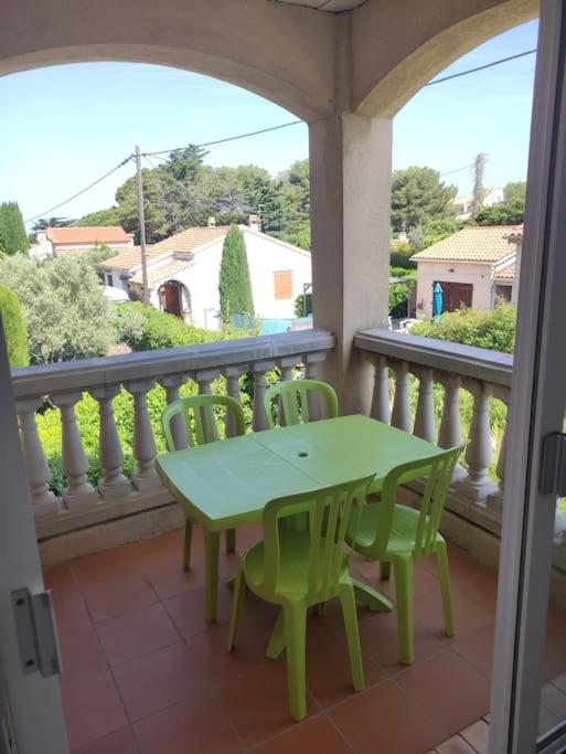 d'une table et de chaises vertes sur un balcon dans l'établissement Appartement proche mer, à Six-Fours-les-Plages