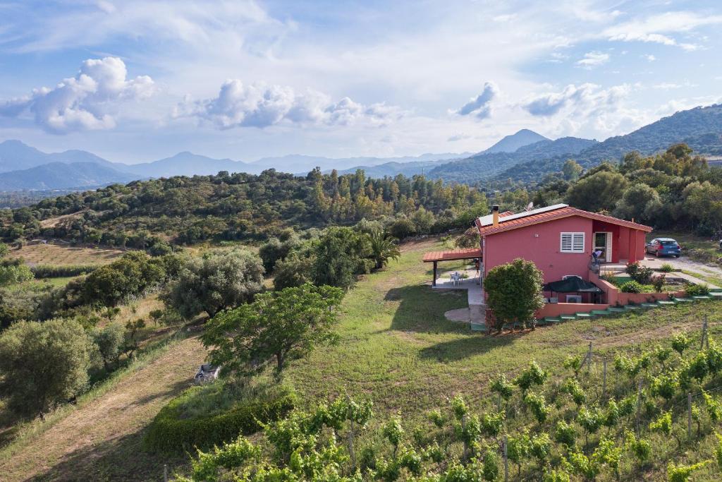 une maison sur une colline avec des montagnes en arrière-plan dans l'établissement La Collina degli Ulivi, à Bari Sardo