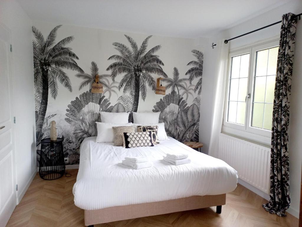 a bedroom with a bed with palm trees on the wall at Le Clos Beauséjour in Montjean-sur-Loire