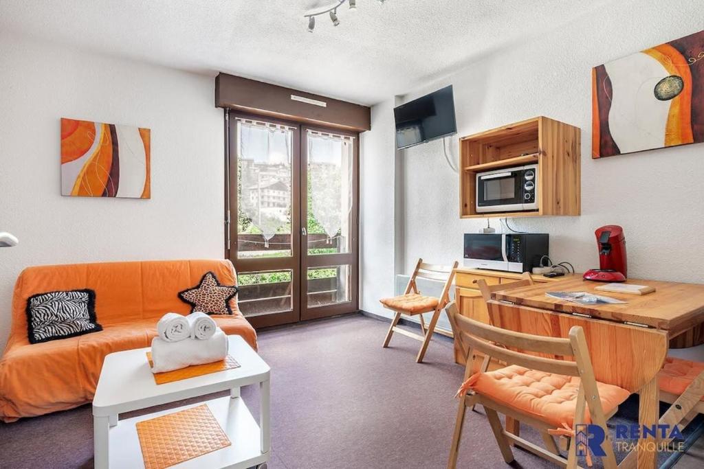 een woonkamer met een oranje bank en een tafel bij Le Capcir - Cosy et lumineux pour se ressourcer in Font Romeu Odeillo Via