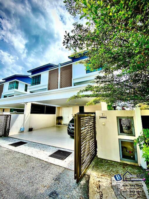 une grande maison blanche avec un portail en face de celle-ci dans l'établissement Batu Ferringhi Luxurious Modern Designed 5BR House, à Batu Ferringhi