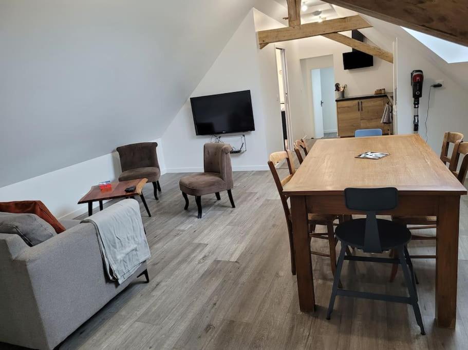 a living room with a table and chairs and a tv at Appartement proche circuit in Changé