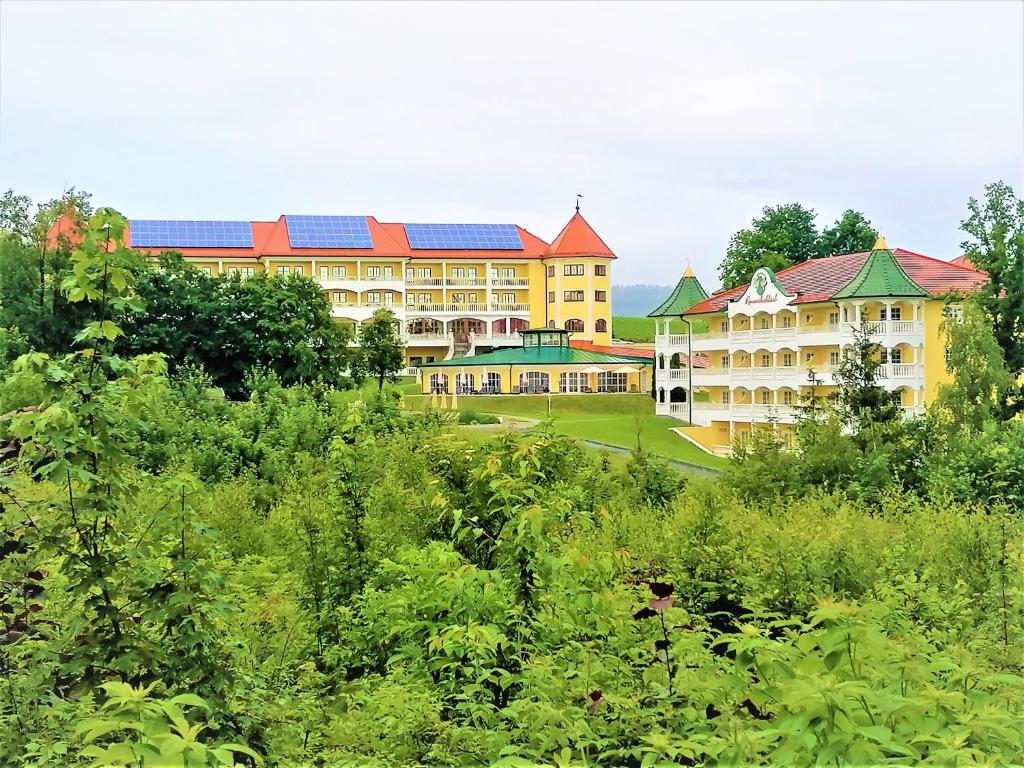 ein großes gelbes Gebäude mit Sonnenkollektoren auf dem Dach in der Unterkunft Wellnesshotel Parkschlössl zu Thyrnau " Adults only" in Thyrnau