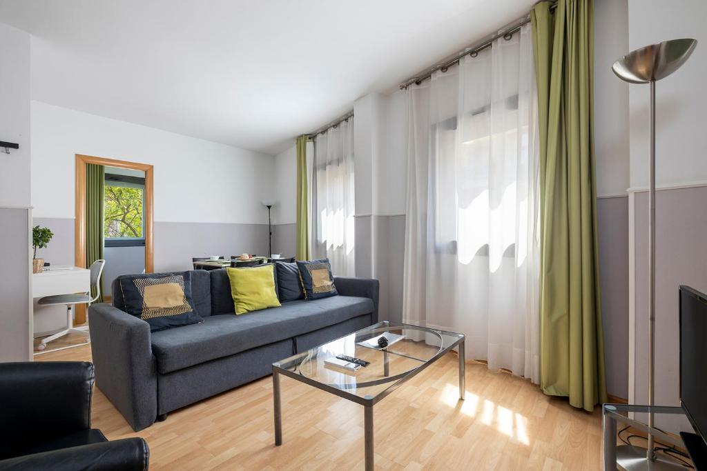 een woonkamer met een blauwe bank en een glazen tafel bij Apartments Sata Park Guell Area in Barcelona