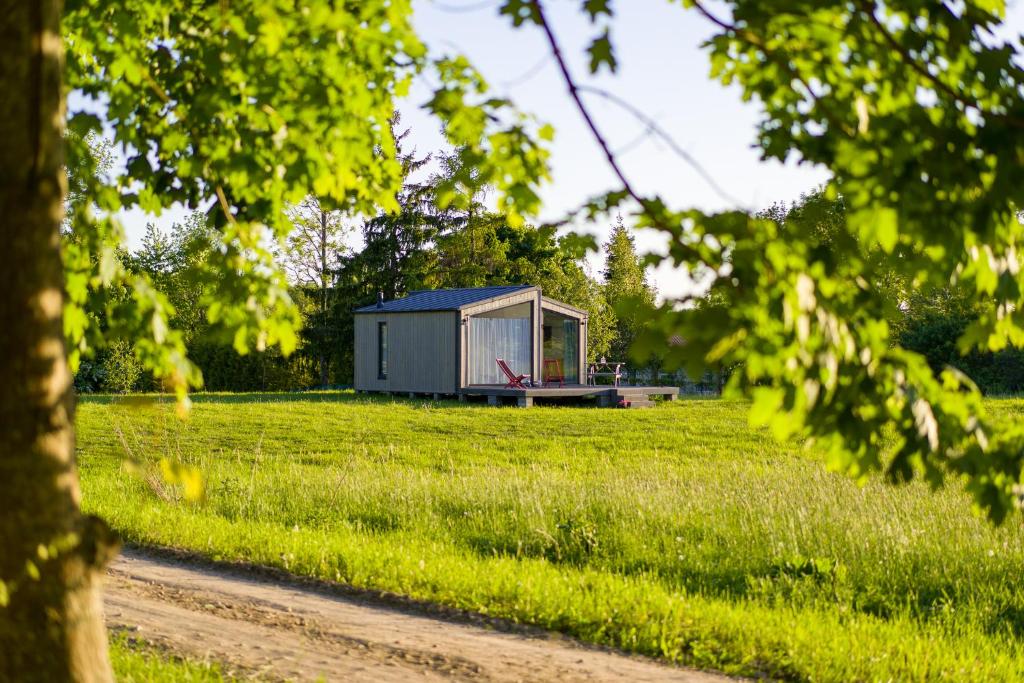 a small shed in a field with a dirt road at Pilwa 17 - Domek in Pilwa