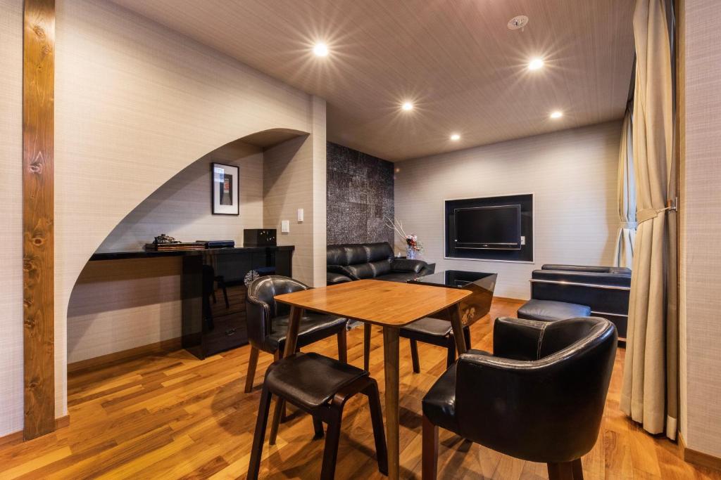 a room with a table and chairs and a tv at Shiki Homes HIGOYA 肥後屋 in Kyoto