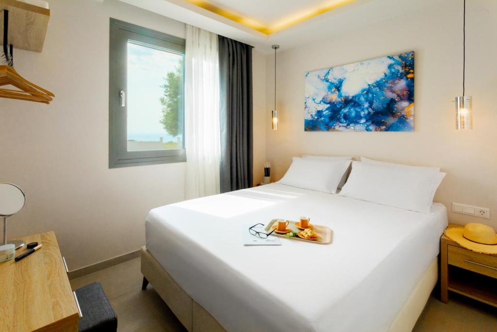 una camera da letto con un grande letto bianco e un vassoio di frutta di Alikon Adult-Only a Néos Marmarás