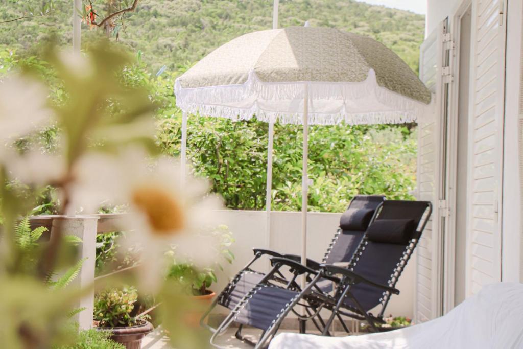 Faros oasis في Gdinj: كرسيين جالسين على شرفة مع مظلة