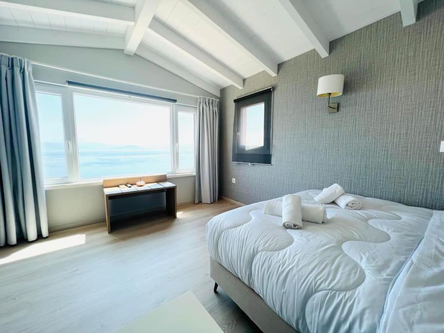 1 dormitorio con cama grande y ventana grande en Green Horizon 3 BR House with Sea View en Benitses