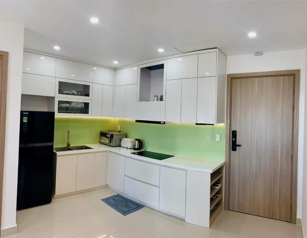 une cuisine avec des armoires blanches et un réfrigérateur noir dans l'établissement Uyên Homestay, à Thôn Văn Dương