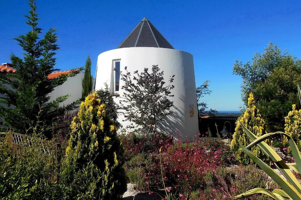 a white building with a steeple in a garden at Salgadinho Casa de Campo & Selao da Eira Velha in São Teotónio