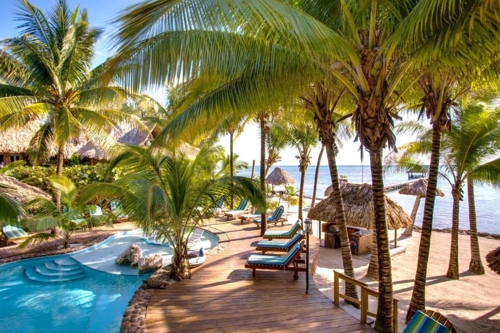 a resort with a pool and palm trees and the ocean at Xanadu Island Resort in San Pedro