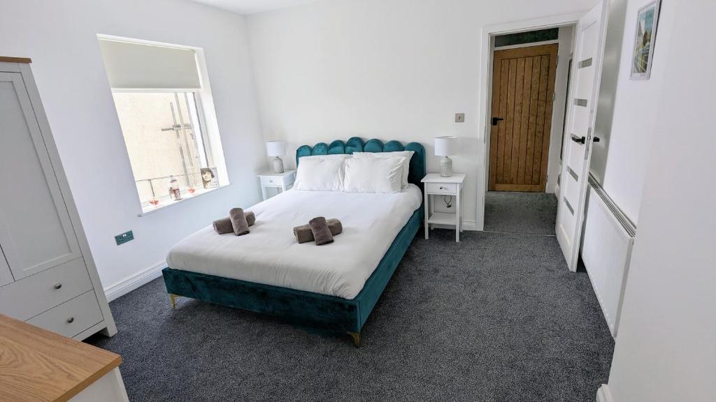 Schlafzimmer mit einem großen Bett mit blauem Kopfteil in der Unterkunft Coastal Hideaway by Seaside Llandudno in Llandudno
