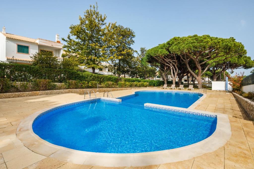 una piscina de agua azul en un patio en Falésia Beach Villa by The Portuguese Butler en Olhos de Água