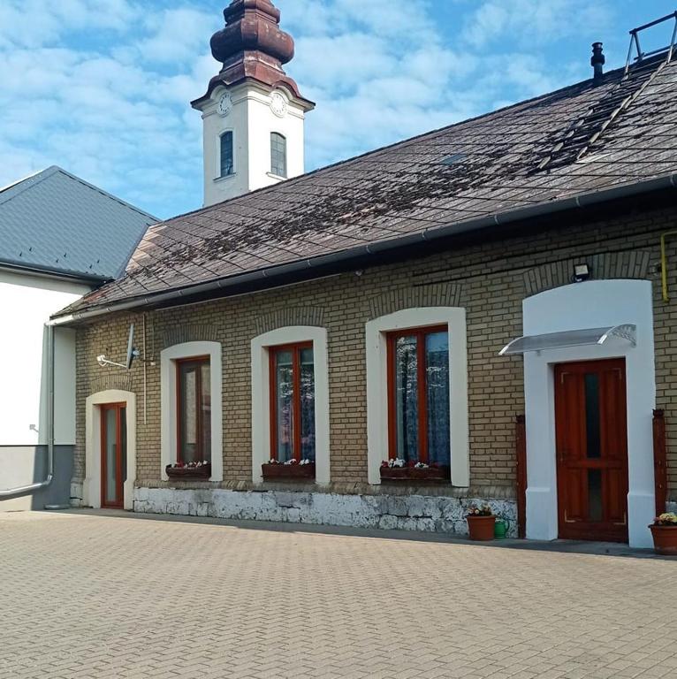 a brick building with a clock tower on top of it at Németh Vendégház -Torkos Fogadó in Ibrány