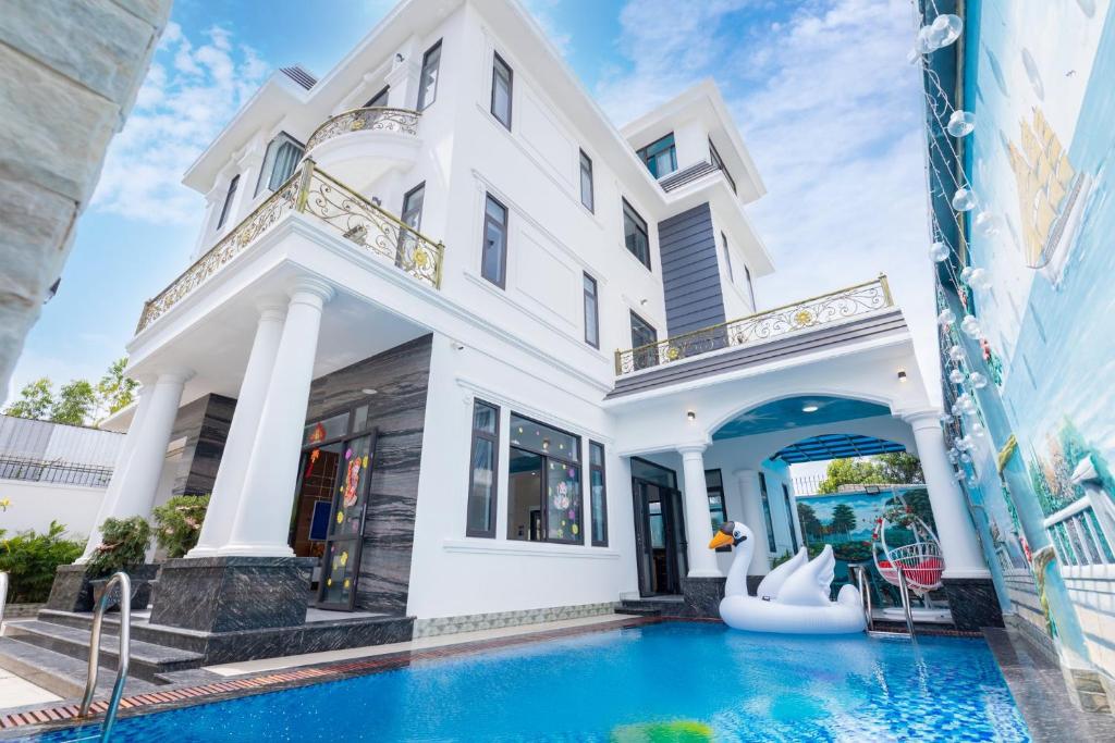 une grande maison blanche avec une piscine devant dans l'établissement Đặng Diễm My Villages C2.49, à Vung Tau