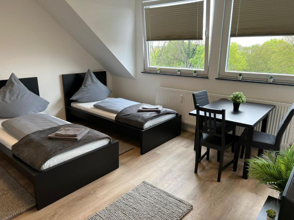 a room with two beds and a table and a table and chairs at ND Hotels & Studio Apartment Mülheim in Mülheim an der Ruhr