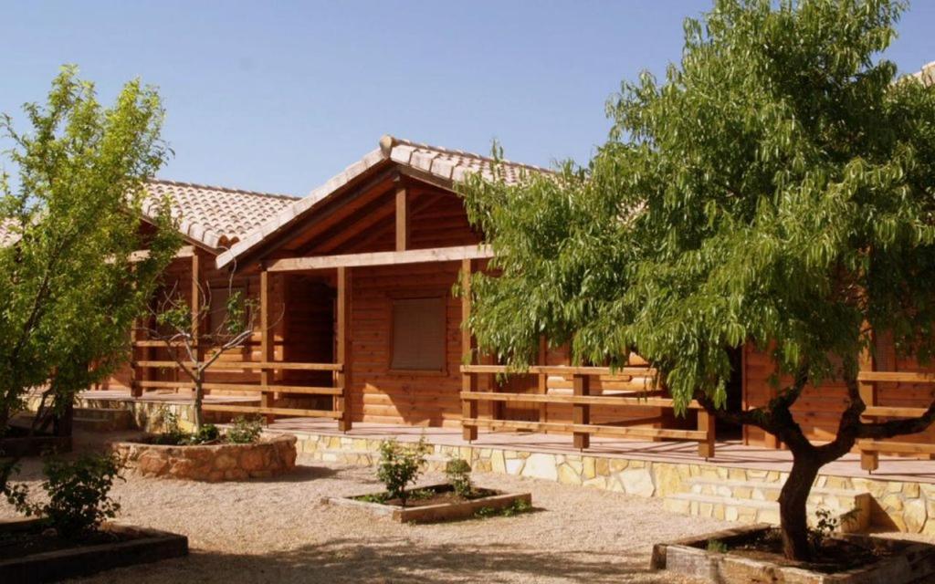 une cabane en rondins avec un arbre en face de celle-ci dans l'établissement Casas de Madera Los Molinos, à Ossa de Montiel