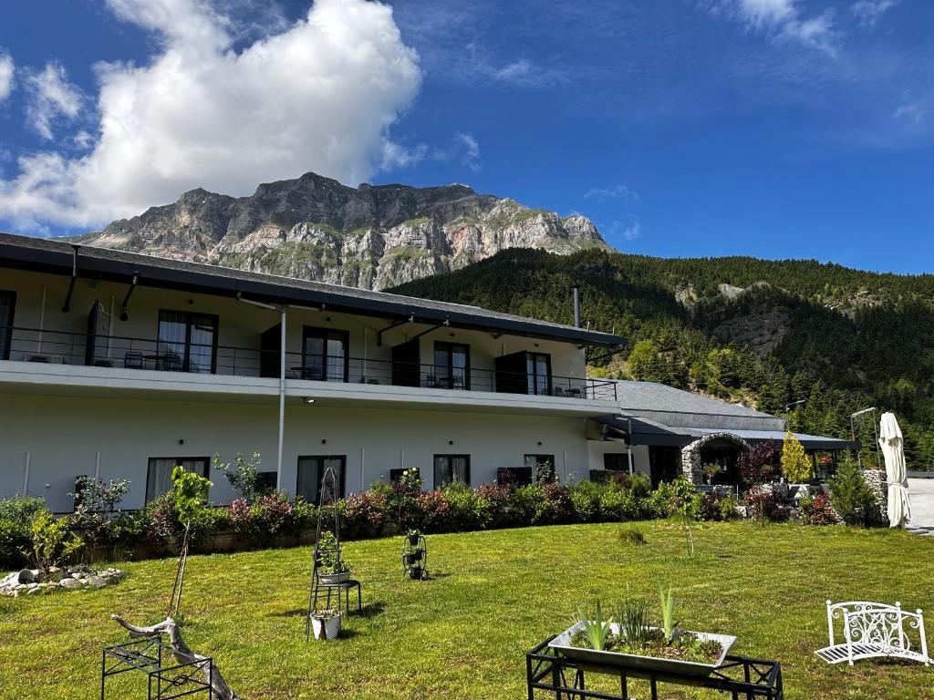 a building with a grass yard with a mountain in the background at Hotel Koferita in Melissourgoi