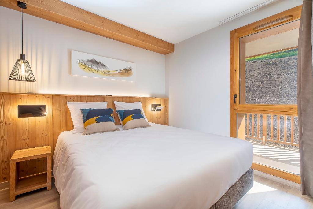 a bedroom with a large white bed and a window at La Cour aux Ecureuils in Peisey-Nancroix