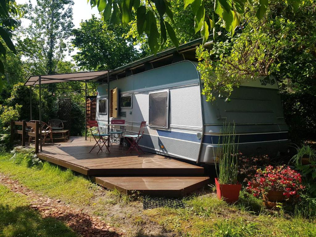 a green and white trailer with a wooden deck at L'hermitage d'Apollon au sein d'un jardin forêt près de l'océan in Mimizan