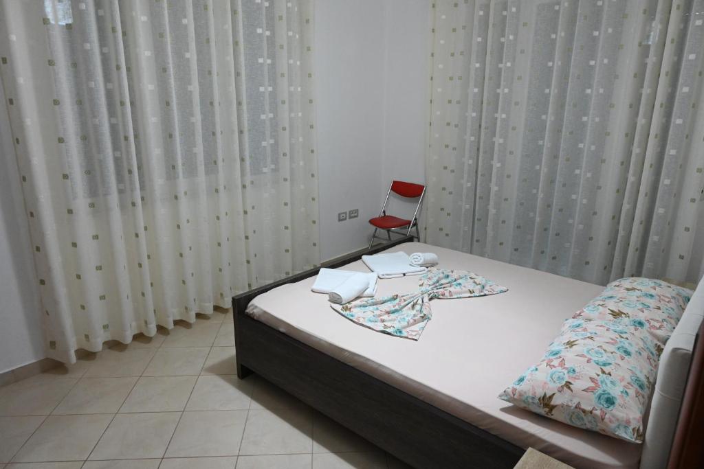 a bedroom with a bed and a red chair at Iris apartaments in Sakës