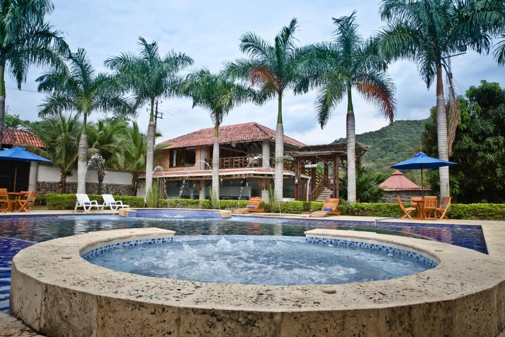 einen Pool in einem Resort mit Palmen in der Unterkunft Hotel Boutique Villas de San Sebastián in Villavicencio