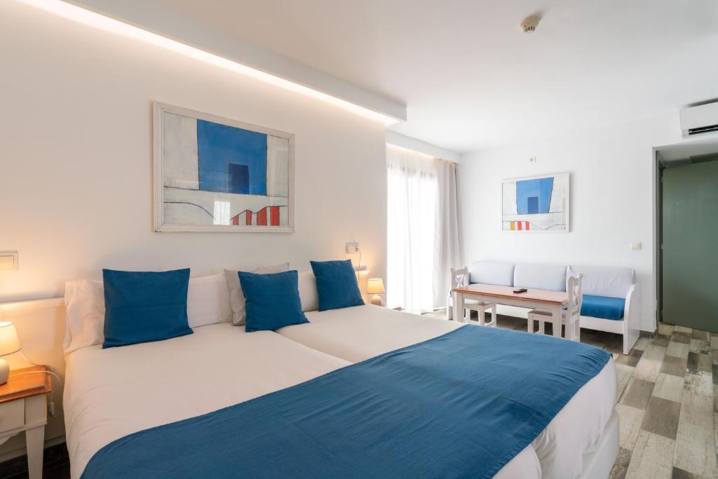 a bedroom with a large bed with blue pillows at Guya Wave Hotel in Cala Ratjada