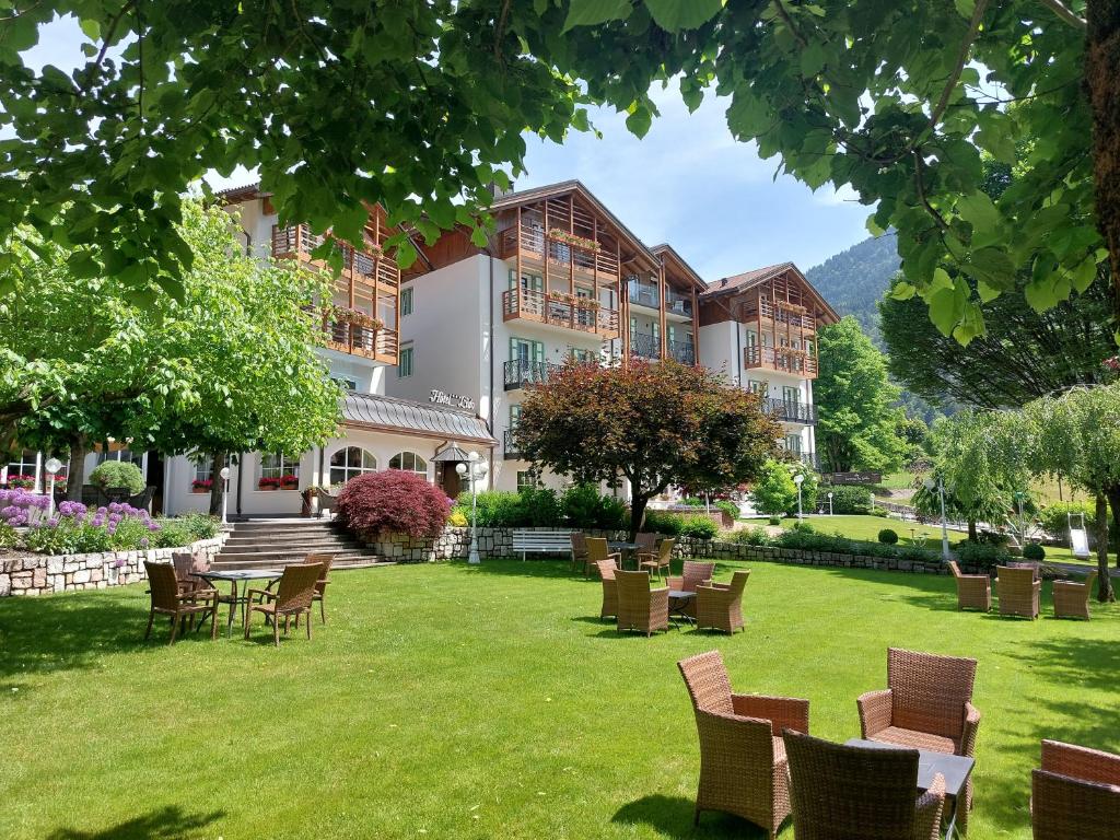 a large building with chairs and tables on a lawn at Hotel Lido - green & slow life in Molveno