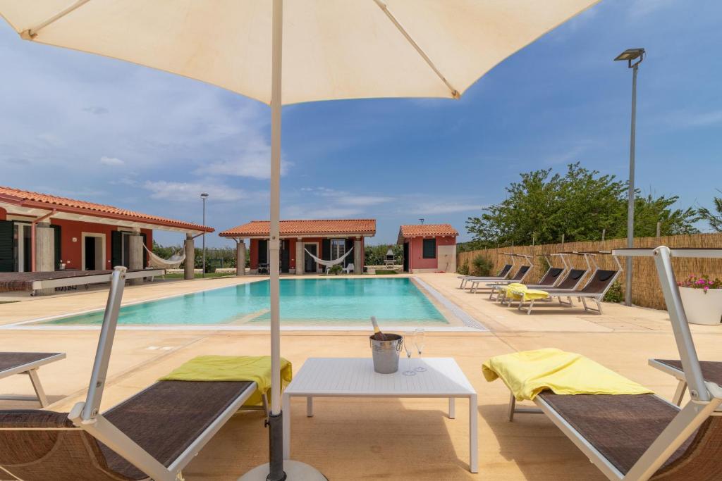 a pool with chairs and a table and an umbrella at Villa melograno in Ispica