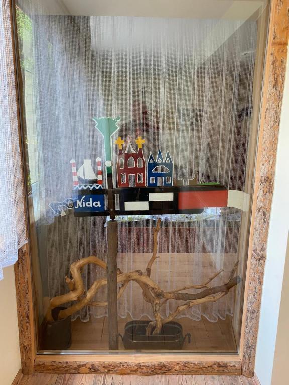 a table in a glass window with a table with a tree at Virgin'A in Nida