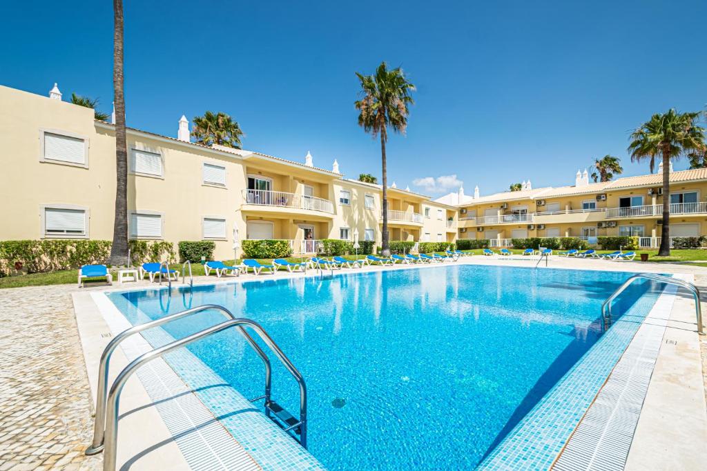 uma piscina num resort com cadeiras e palmeiras em BeGuest Jardins Vale Parra Apartment em Albufeira