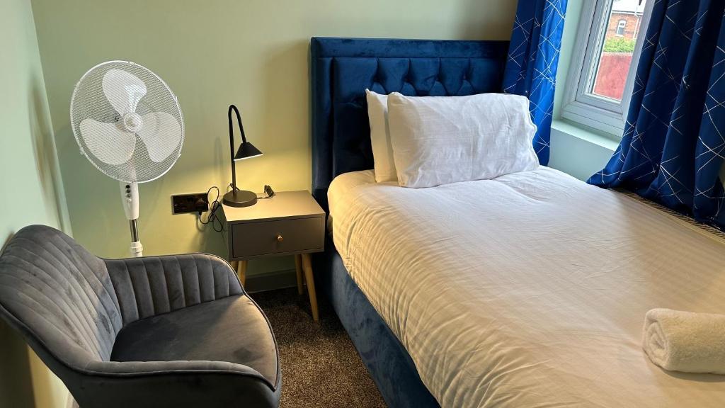 een slaapkamer met een bed, een stoel en een ventilator bij Homestay in Walsall in Walsall