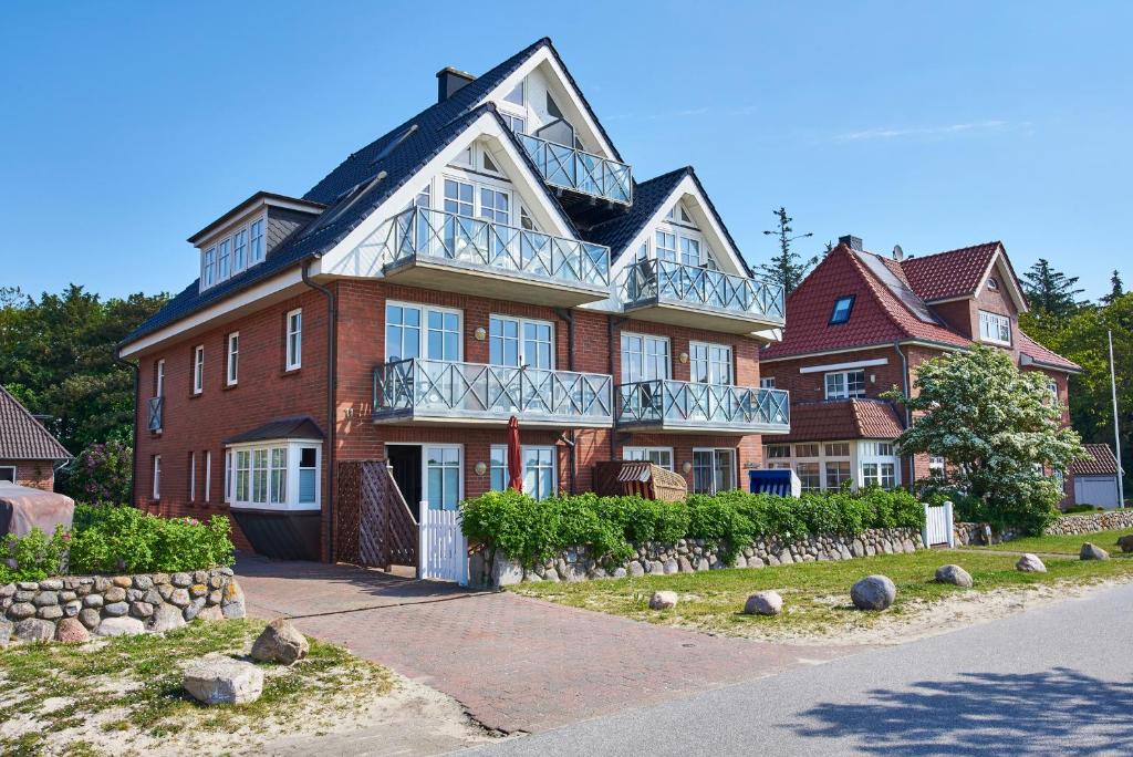 uma grande casa de tijolos vermelhos com uma varanda em Hardina Whg 3, Stockmannsweg em Wyk auf Föhr