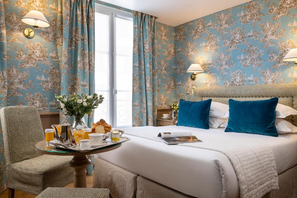 a hotel room with a bed with blue walls and a table at Hotel du Champ de Mars in Paris