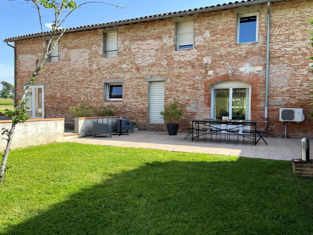 un edificio in mattoni con patio e tavolo di Les Terrasses Binel à Ronsac ad Aigrefeuille