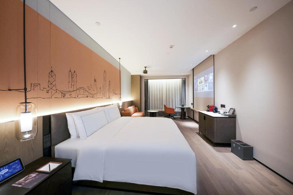 a hotel room with a large bed and a desk at UrCove by HYATT Shenzhen Luohu in Shenzhen