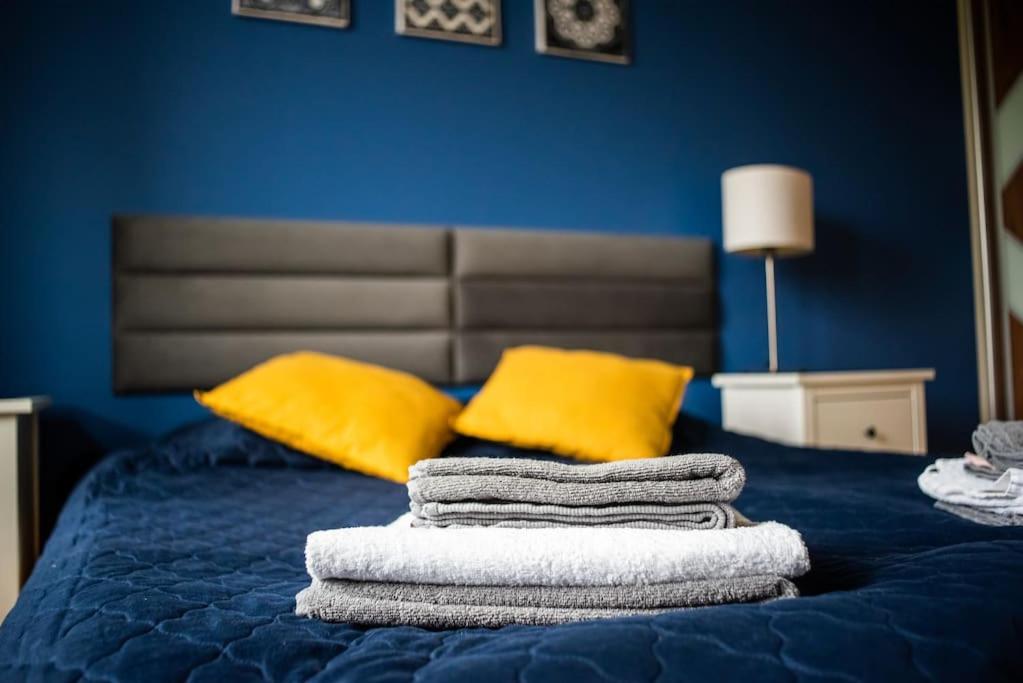 una pila de toallas en una cama con almohadas amarillas en Citilife Apartament dla 4 osób, en Gdansk