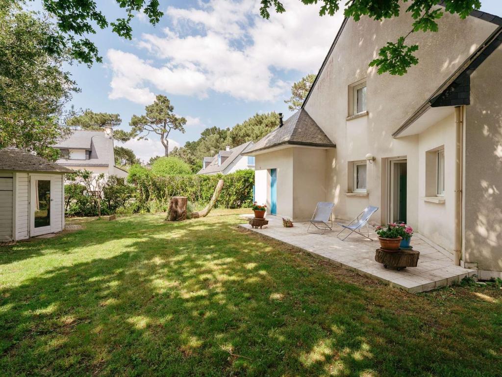 une cour avec deux chaises et une maison dans l'établissement Maison spacieuse à Carnac, proche plage, 3 terrasses, jardin clos, Wifi, pour 7 pers, 2* - FR-1-477-220, à Carnac